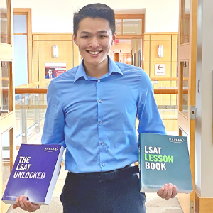 A photo of a Denison student holding Kaplan LSAT test prep books.